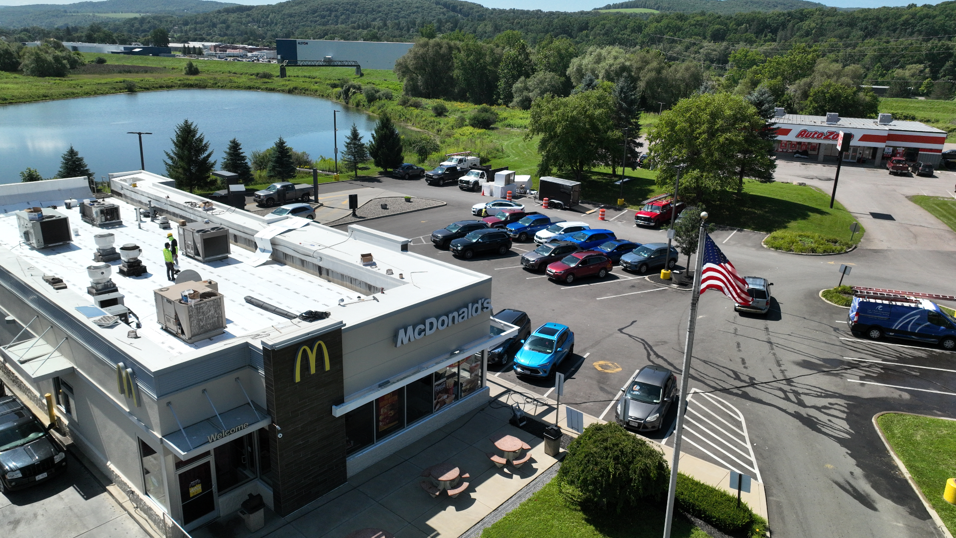 Crew installing a white membrane roof on a commercial building, seen from a drone